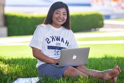 Student sitting on lawn by A Building